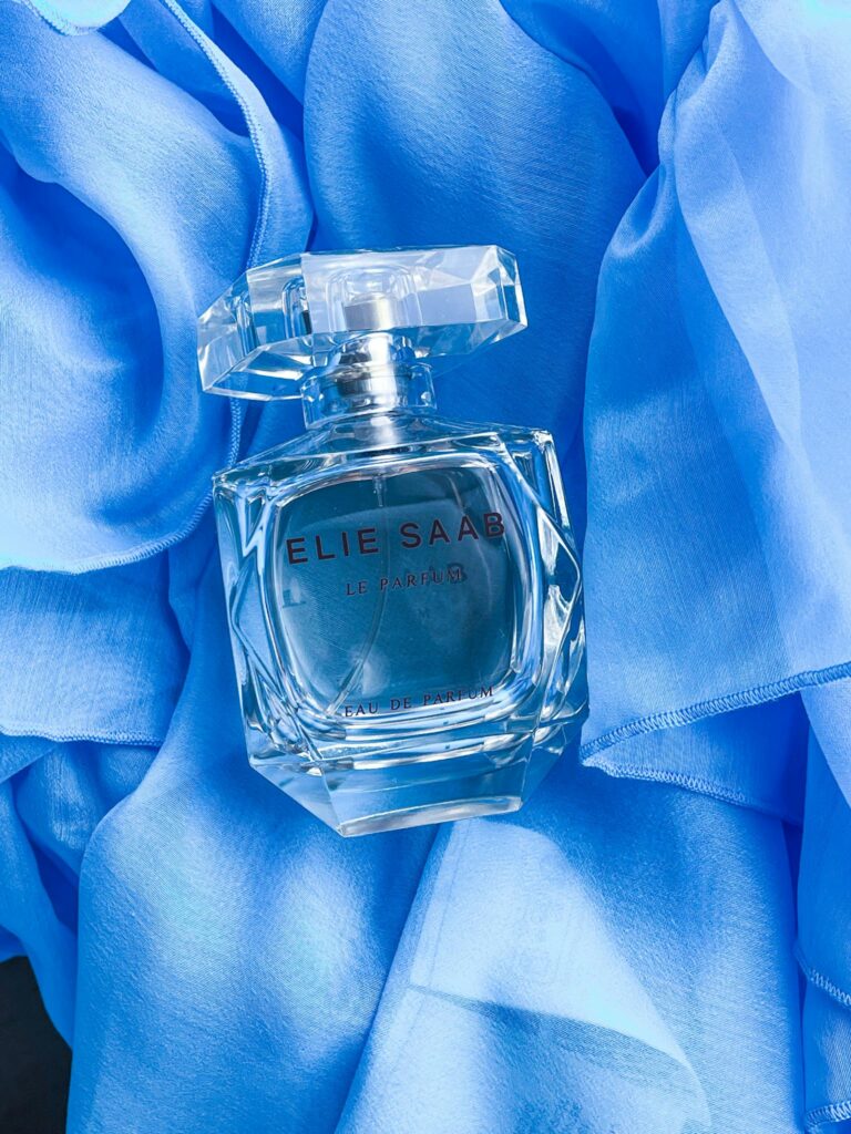 A stylish Elie Saab perfume bottle displayed on luxurious blue fabric, exuding elegance.