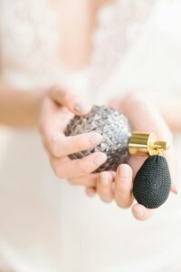 Gentle close-up of feminine hands delicately holding a vintage style perfume bottle.