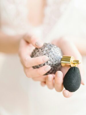 Gentle close-up of feminine hands delicately holding a vintage style perfume bottle.