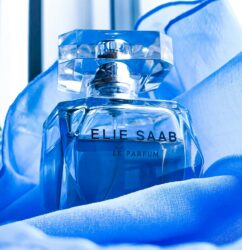 Luxurious Elie Saab perfume bottle displayed on soft blue silk fabric.